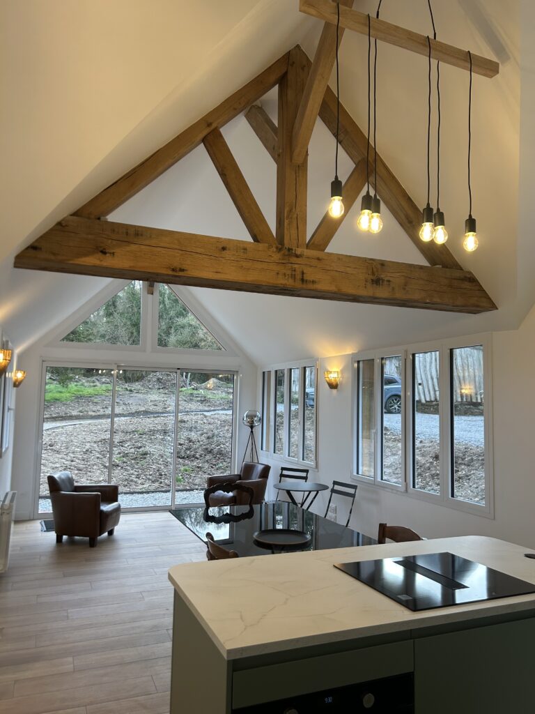 Intérieur longère normande avec poutres chêne apparentes et volumes généreux ancienne grange